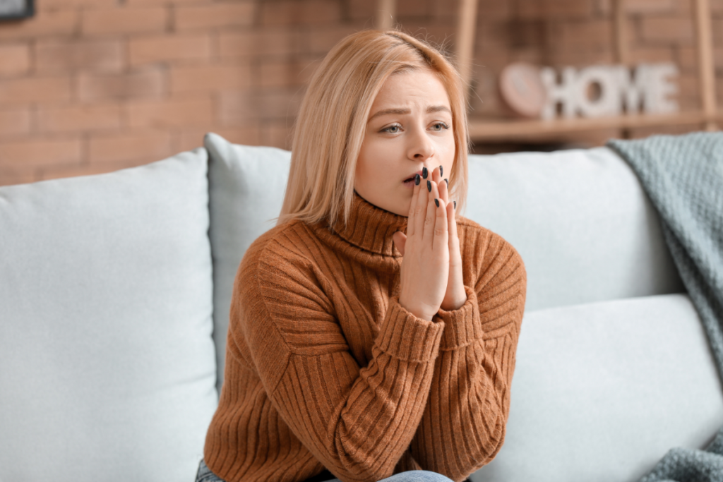 Women in a high-control religion sitting on couch with distressed expression due to intimate partner abuse