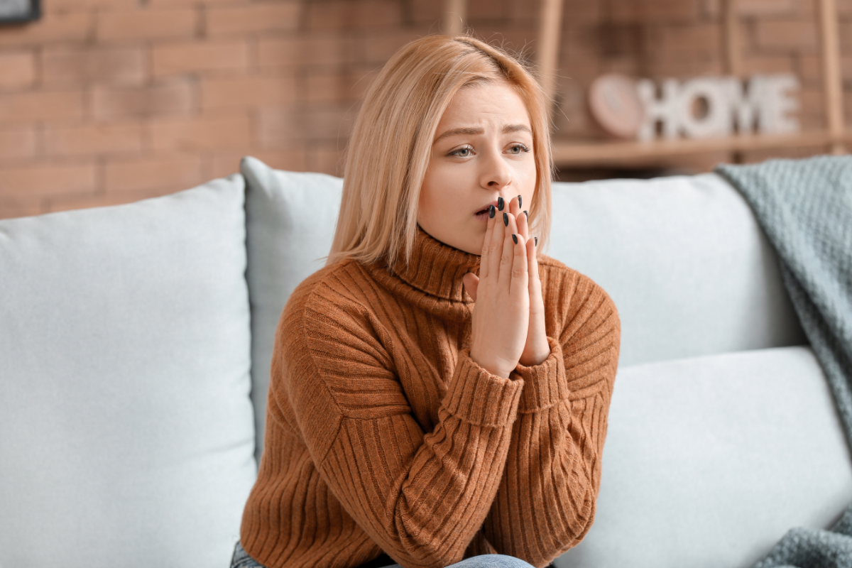 Women in a high-control religion sitting on couch with distressed expression due to intimate partner abuse