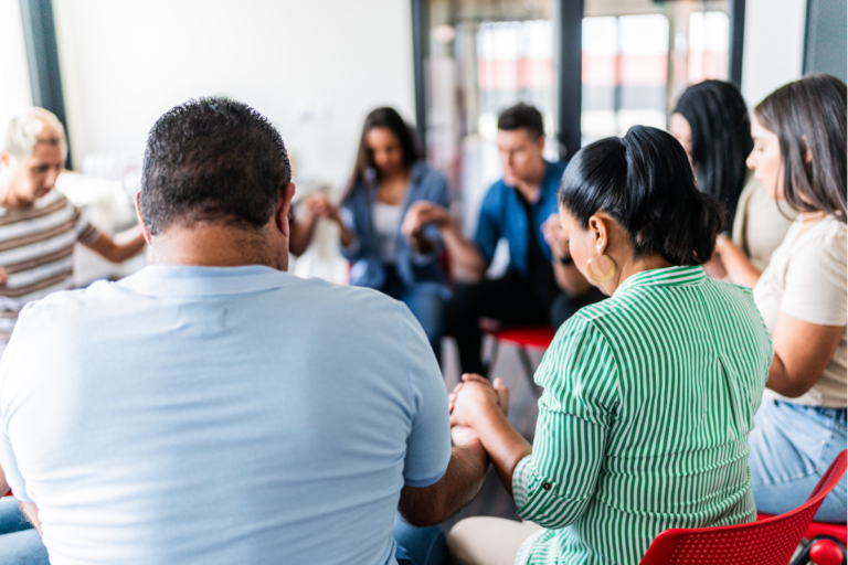 People in a religious cult sitting in a circle holding hands and praying.
