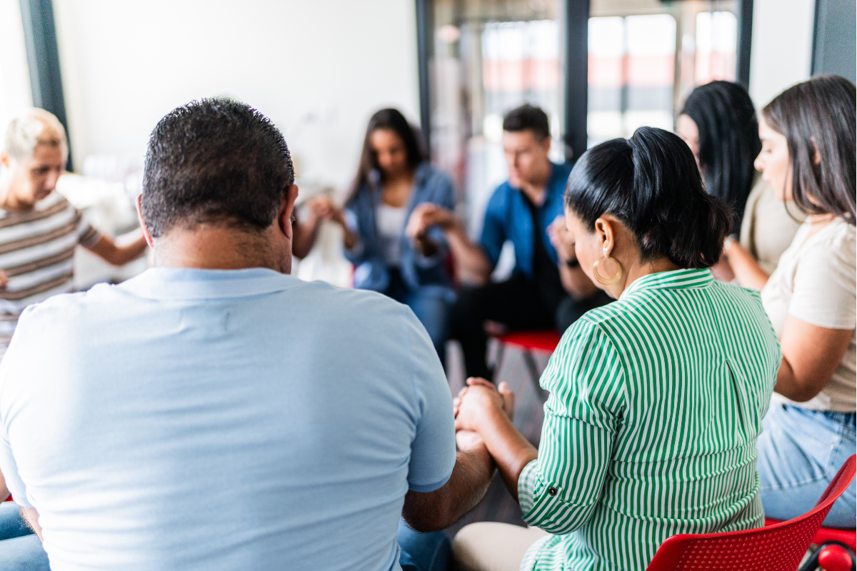 People in a religious cult sitting in a circle holding hands and praying.
