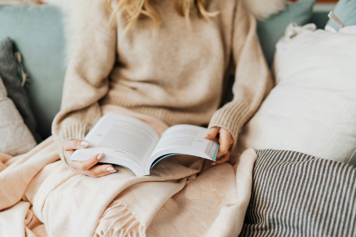 Neurodiverse woman reading a book while sitting on a couch learning about fundamentalism