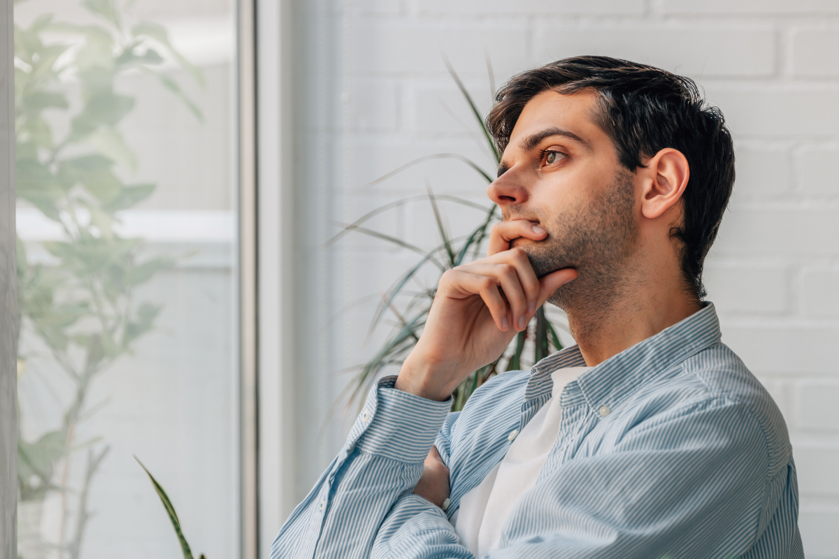 Man looking out the window with chin on hand