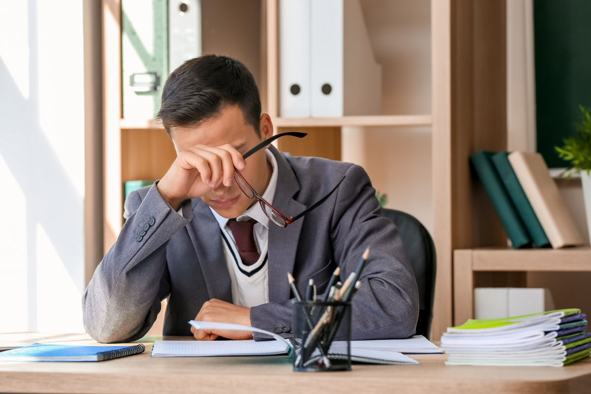 Man leaning forehead on hand at his desk feeling overwhelmed by the expectations of purity culture.