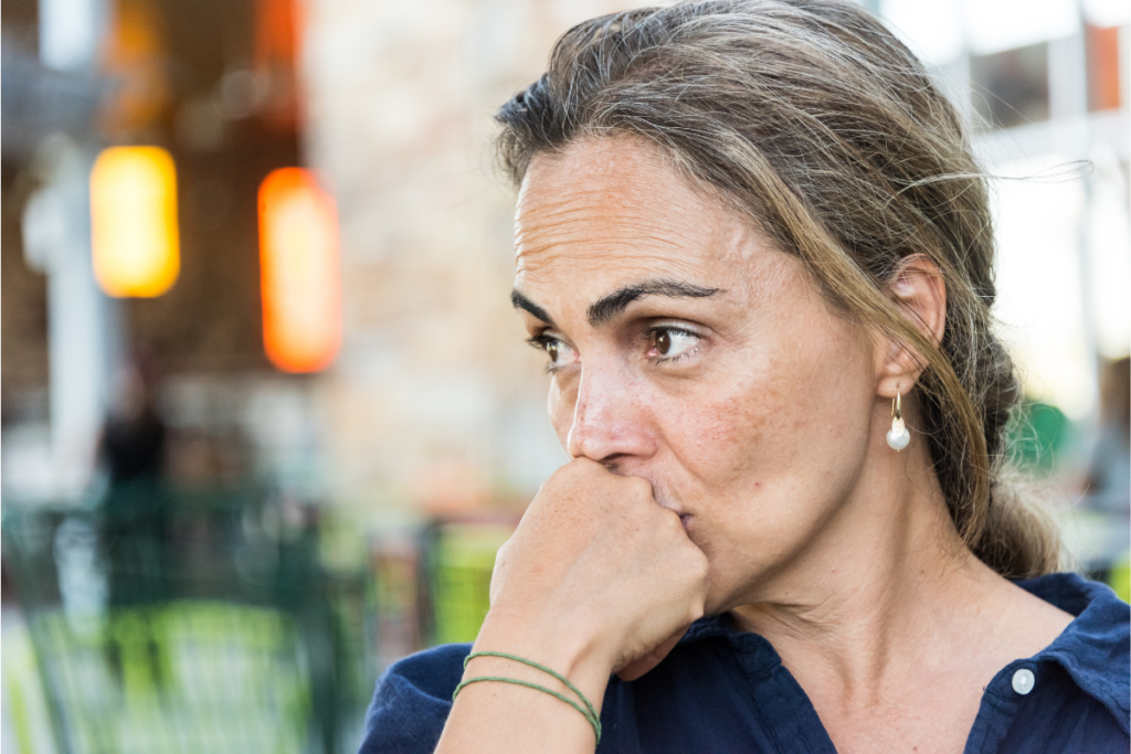 Woman with hand on chin looking concerned. She is experiencing hyper-vigilence which is the result of religious trauma manifesting in physical symptoms