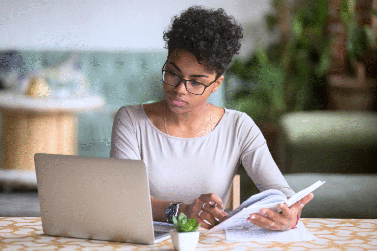 a woman sitting at a table with a laptop and a book research religious cult programming