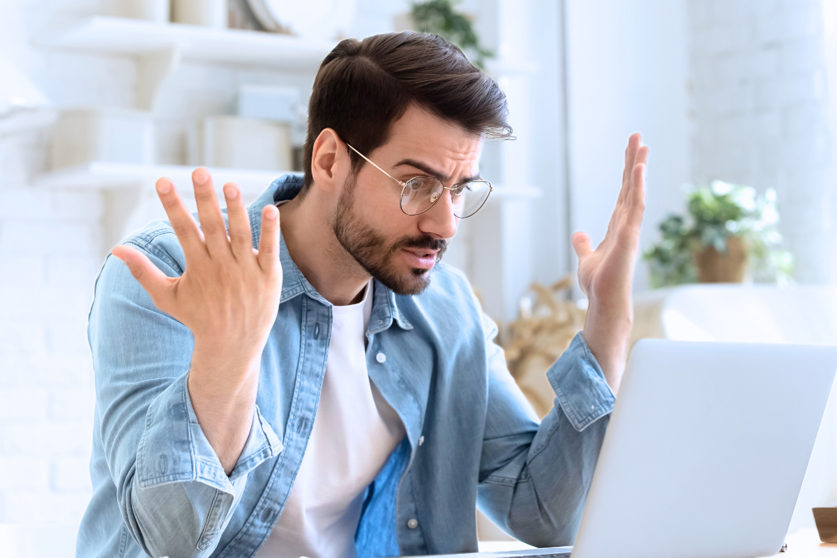 Man looking at laptop and experiencing emotional dysregulation due to an insecure attachment style that resulted from an authoritarian religious upbringing