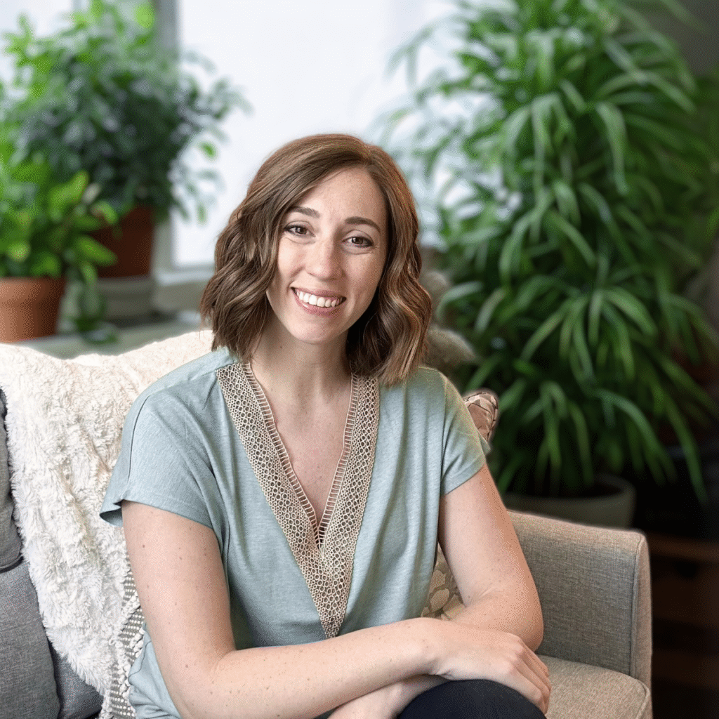 An image of Megan sitting on a couch with green plants in the background