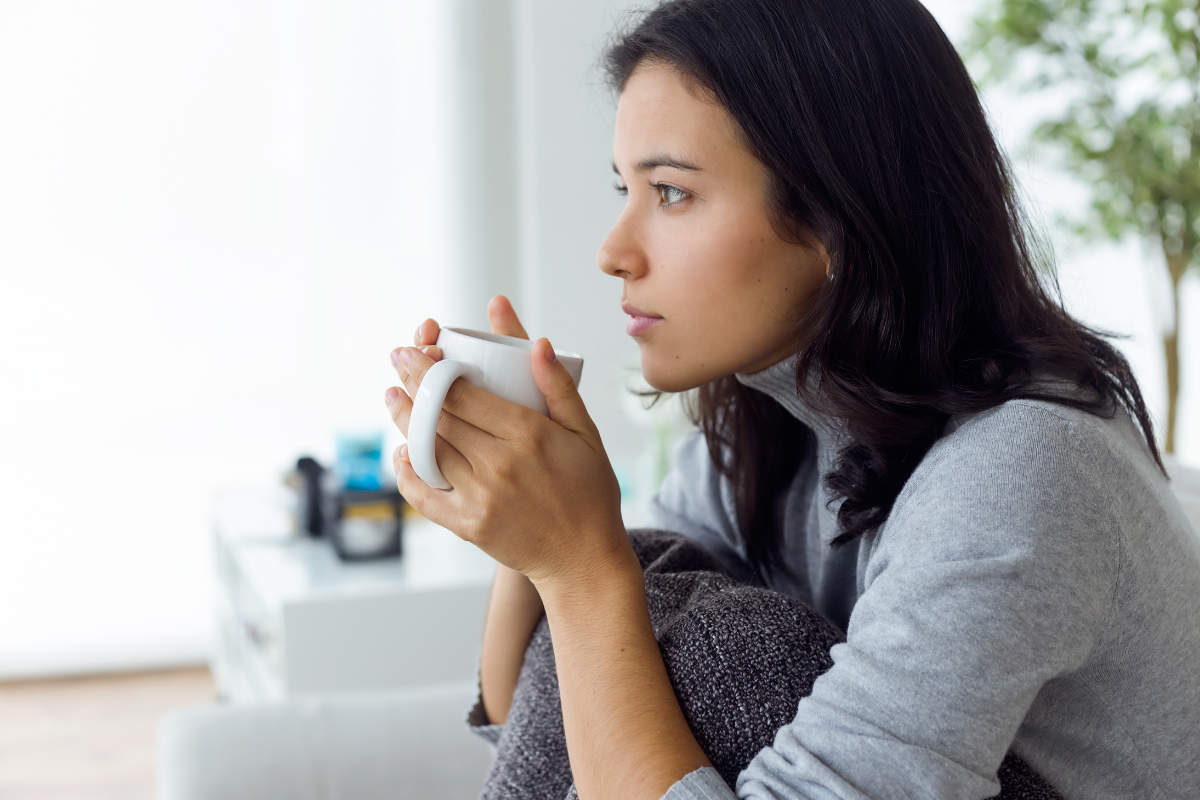 Woman holding a cup, cozy atmosphere contemplating her life post-deconversion